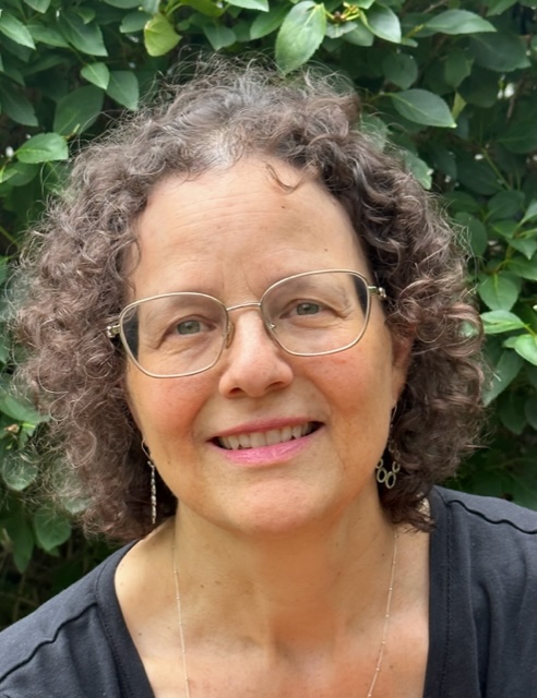 Judith in front of foliage looking at the camera and smiling