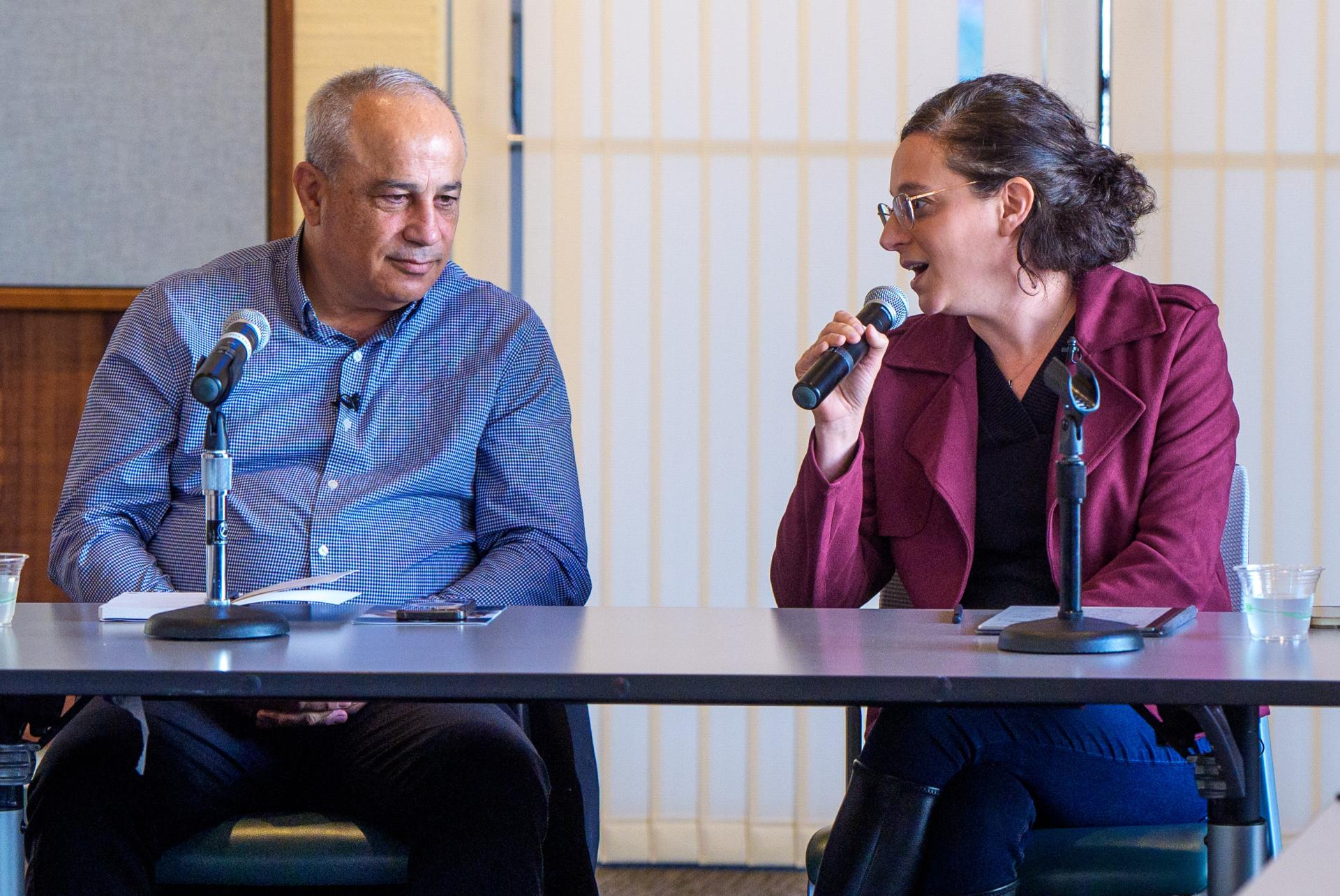 Mohammad speaking with a woman while both of them are behind a table 